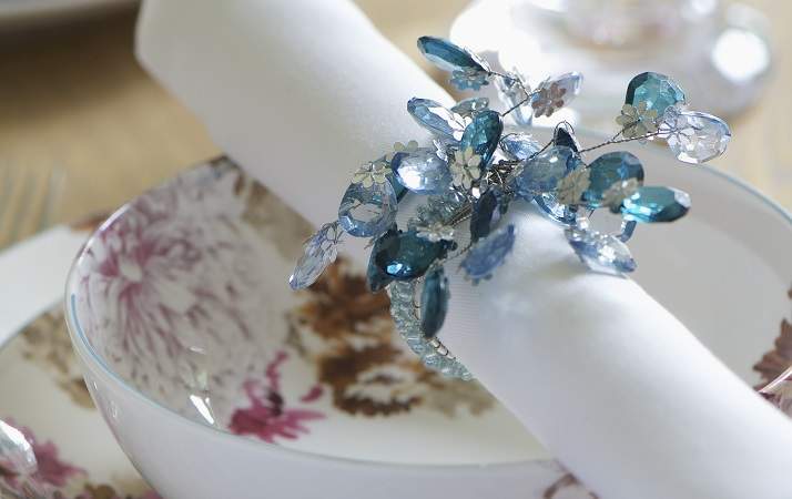 Festive place setting with floral crockery and linen napkin in beaded napkin ring