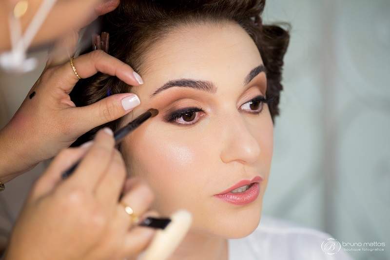 Maquiagem em tons terrosos nos olhos, pele fresh e batom rosado com cintilância.